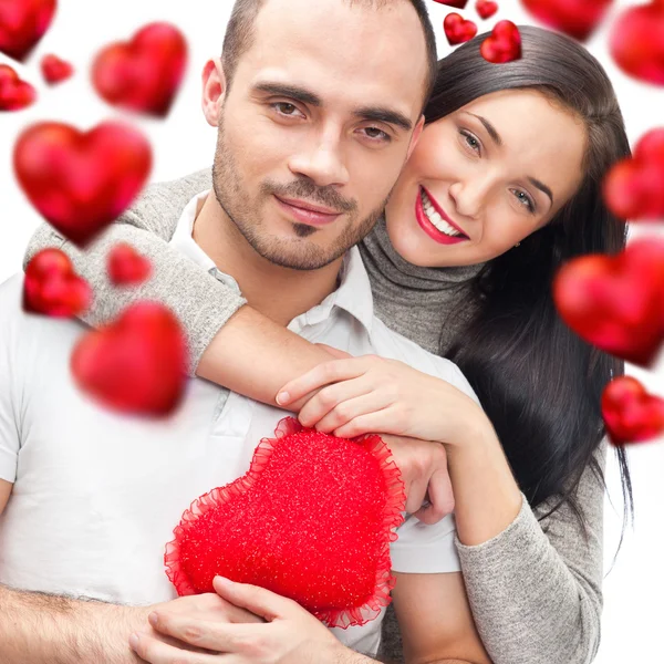 Krásná mladá láska pár objímat proti Bílému pozadí a mnoho červené srdce, létající kolem nich — Stock fotografie