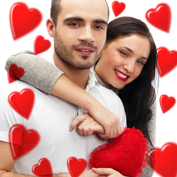 Bella giovane coppia d'amore che si abbraccia su uno sfondo bianco e molti cuori rossi che volano intorno a loro — Foto Stock