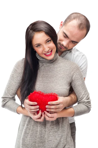 Šťastný mladý dospělý pár s červeným srdcem na bílém pozadí, všeobjímající a směje se — Stock fotografie