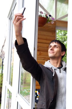 Young man trying to catch connection, holding his mobile phone up clipart