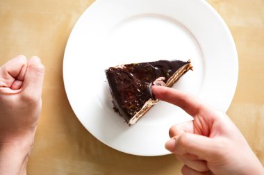 Delicious french chocolate cake on white plate on table. Woman arms near it. Top view. Sweet breakfast. clipart