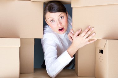 Portrait of young woman surrounded by lots of boxes. Lots of work concept. clipart