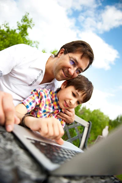 행복 한 가족의 초상화를 근접 촬영: 아버지와 벤치에 앉아 그들의 뒤뜰에서 옥외 휴대용 퍼스널 컴퓨터를 사용 하 여 그의 아들 — 스톡 사진