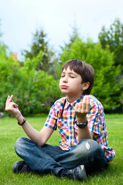 Photo of adorable young wise boy sitting on the grass at his backyard — Stock Photo, Image