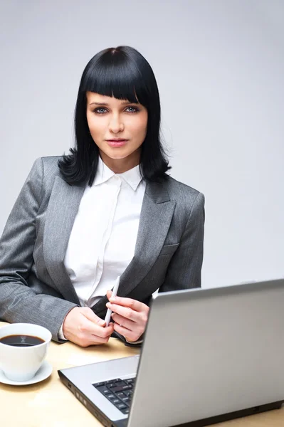 Schöne Geschäftsfrau denkt über etwas nach, während sie in ihrem Büro am Computer arbeitet — Stockfoto