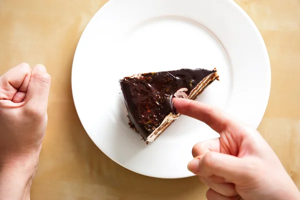 테이블에 흰 접시에 맛 있는 프랑스 초콜릿 케이크. 근처 여자 팔입니다. 상단으로 보기입니다. 달콤한 아침 식사. — 스톡 사진