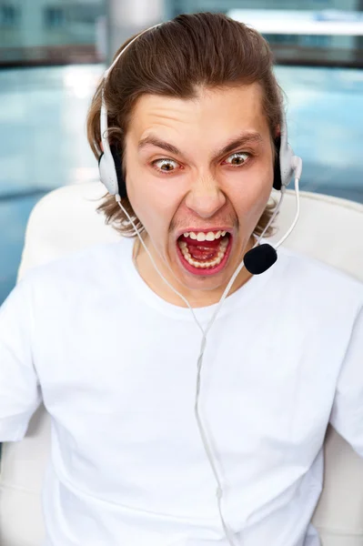Closeup of angry screaming customer service executive or student with headphones listening online lecture — Stock Photo, Image