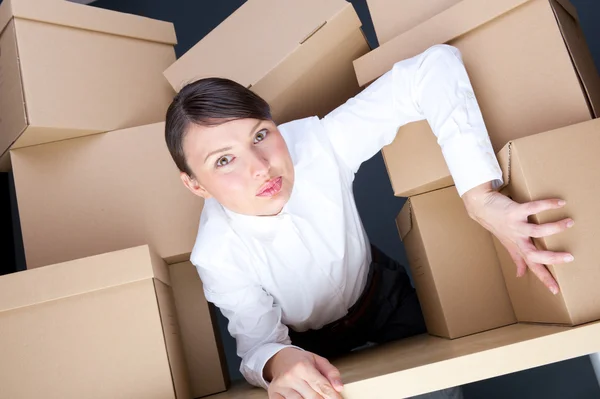 Portrait of young woman surrounded by lots of boxes. Lots of work concept. — Stock Photo, Image