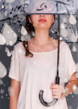 Portrait of beautiful young fashionable woman standing under umbrella and catching fake water drops of rain. Safety concept clipart