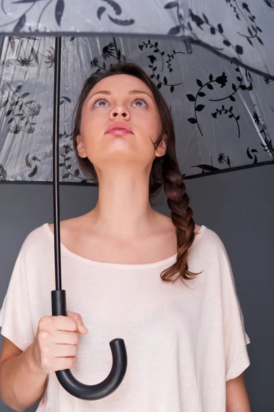 Joven mujer de moda sosteniendo paraguas de pie sobre fondo gris —  Fotos de Stock
