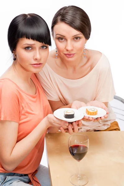 Mujeres alegres comiendo rollos de sushi y bebiendo vino tinto — Foto de Stock