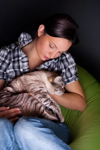 Szczęśliwa młoda kobieta z kotem, złagodzone na kanapie beanbag. — Zdjęcie stockowe
