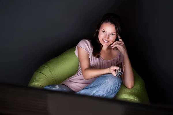 Gelukkig jonge vrouw holding afstandsbediening en romantische film door tv kijken — Stockfoto