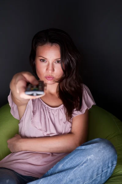 Молодая женщина смотрит телевизор сидя на мешок с бобами дома — стоковое фото
