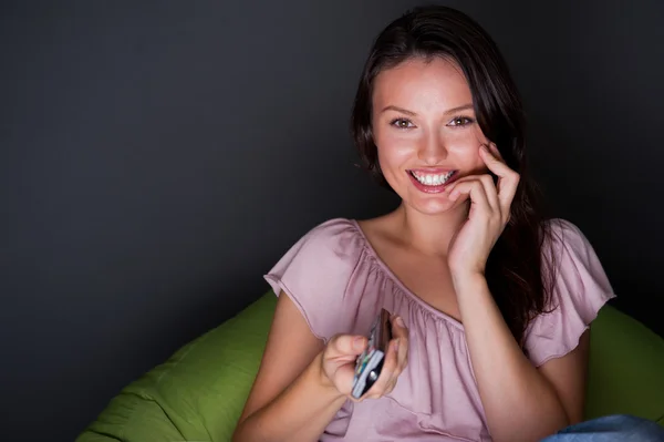 Happy young woman holding remote control and watching romantic movie by tv — Stock Photo, Image