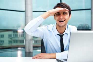 Closeup portrait of businessman looking for employees. Sitting indoors at his office in front of laptop and looking at camera clipart