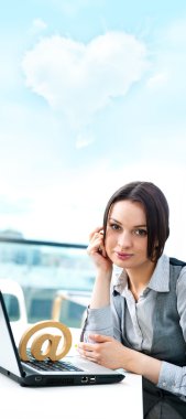 Portrait of a cheerful Business woman sitting on her desk with an at symbol and thinking about love clipart