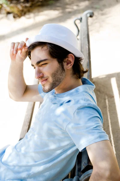 Güneşin parkta bankta otururken yakışıklı bir genç adam portresi — Stok fotoğraf