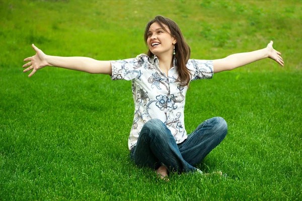 Piena lunghezza di bella giovane donna che riposa sull'erba e sorride. Saluto a braccia aperte — Foto Stock