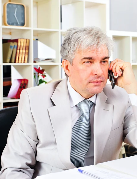 Retrato de un hombre de negocios mayor sentado junto a su teléfono en la oficina —  Fotos de Stock
