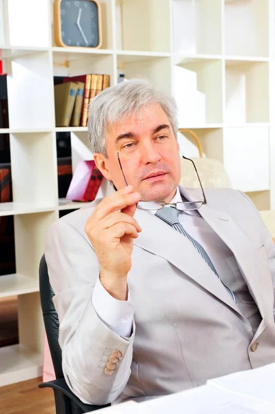 Porträt eines leitenden Geschäftsmannes, der im Büro sitzt und über etwas nachdenkt — Stockfoto