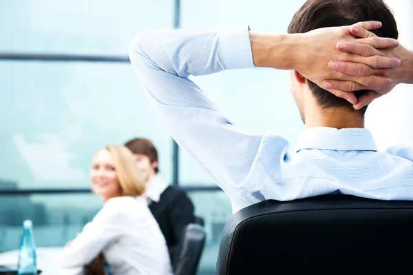 Retrato de primer plano de un joven empresario descansando y sus colegas trabajando en la parte posterior —  Fotos de Stock