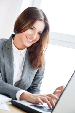 Beautiful business woman dreaming while working on computer at her office clipart