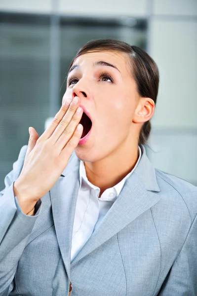 A young, pretty European business woman at office building yawning — Stock Photo, Image