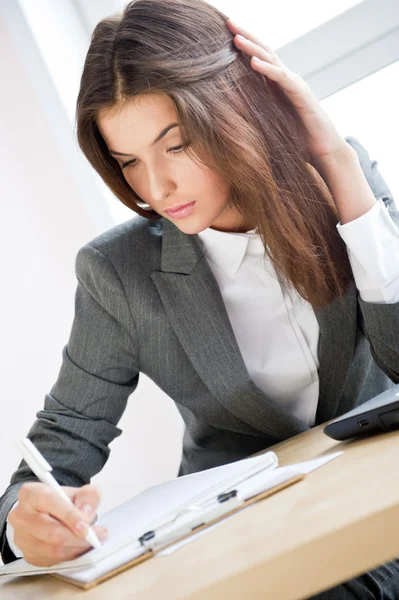 Schöne Geschäftsfrau signiert Dokumente, die am Computer in ihrem Büro arbeiten — Stockfoto
