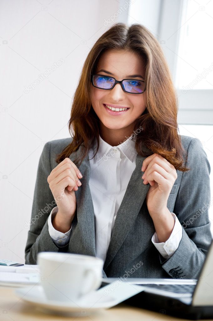 Young businesswoman smiles while working on a computer. Vertical shot.