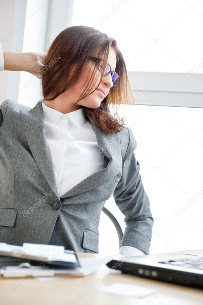 Beautiful business woman is very busy and a little bit tired while working at her office