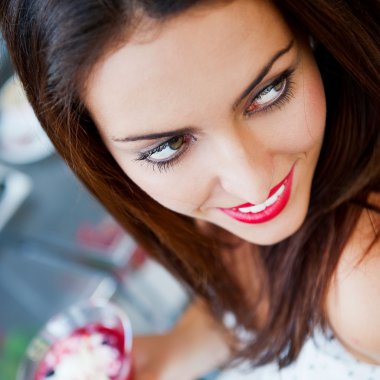 Portrait of an young beautiful woman eating an ice cream in cafe clipart