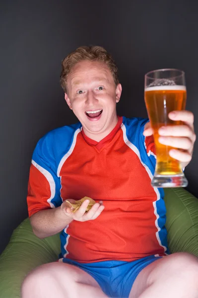 Retrato de jovem assistindo TV tradução do jogo de futebol com sua equipe favorita e beber cerveja — Fotografia de Stock