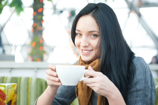 Nahaufnahme Porträt einer hübschen jungen Frau, die eine Tasse Kaffee trinkt, während sie sich im Café ausruht — Stockfoto