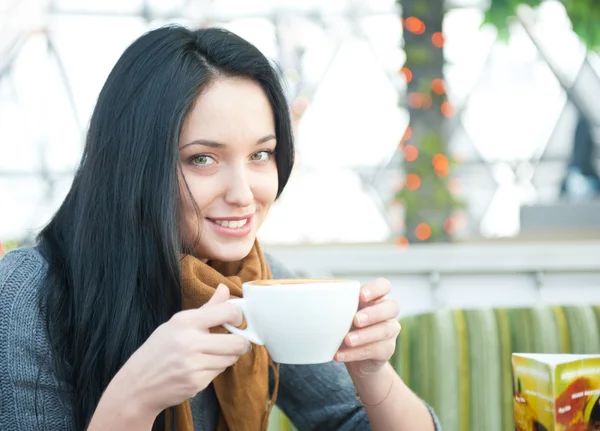 Closeup πορτρέτο του ένα αρκετά νεαρό θηλυκό με το ένα φλιτζάνι του καφέ ανάπαυσης στο café, ενώ — Φωτογραφία Αρχείου