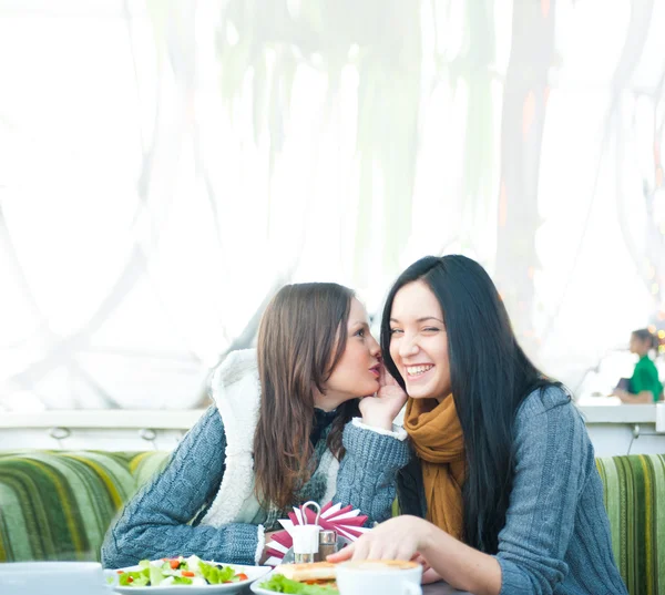 Två vackra kvinnor dricka kaffe, äta lunch och chattar på café — Stockfoto