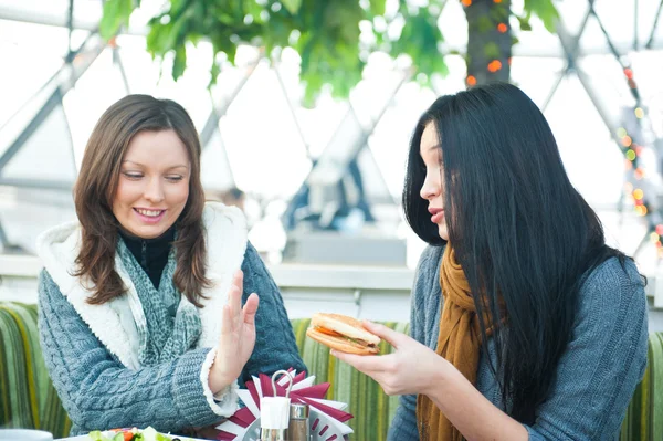 Två vackra kvinnor dricka kaffe, äta lunch och chattar på café — Stockfoto