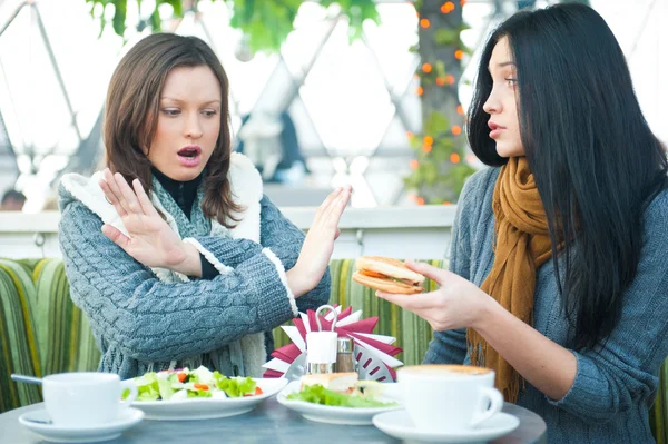 Two beautiful women having lunch and chatting at cafe. One of them saying stop to one more sandwich — Stock Photo, Image