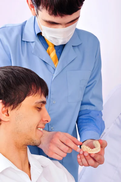 Um jovem paciente do sexo masculino em um consultório odontológico olhando para gesso elenco de seus dentes — Fotografia de Stock
