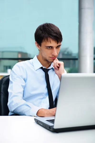 Молодой человек сидит перед ноутбуком в офисе — стоковое фото