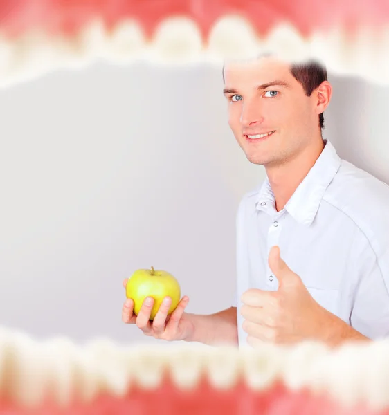 Рот с зубами изнутри и стоматолог держит зеленое яблоко и большие пальцы вверх — стоковое фото