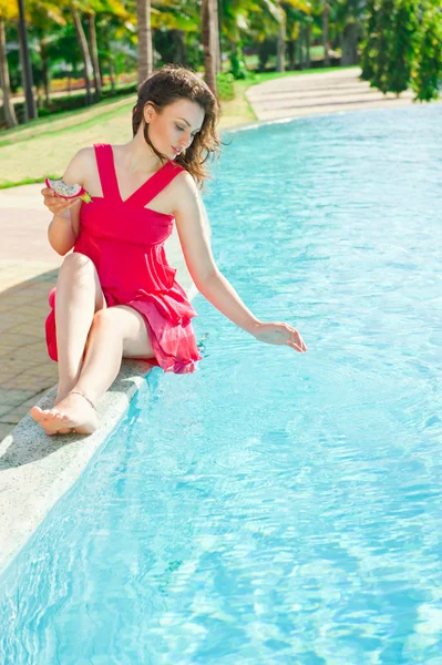 Woman sitting in a swimming pool and eating dragon fruit — Stock Photo, Image