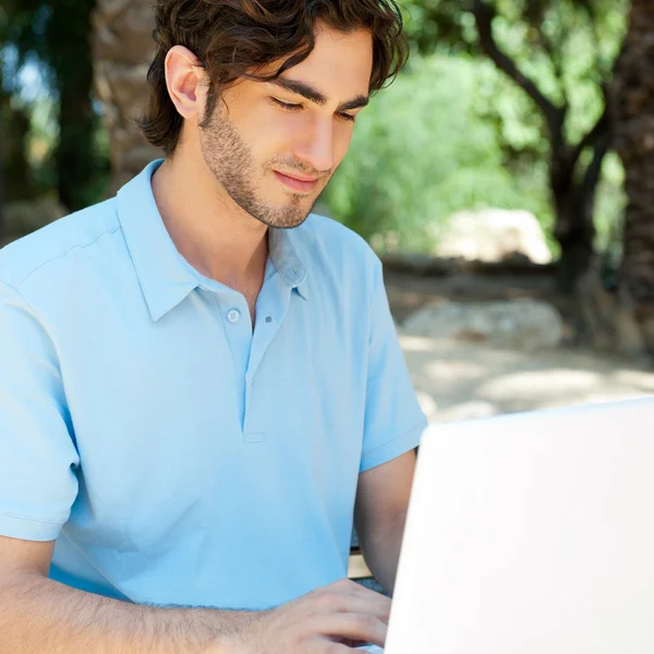 一个年轻人与笔记本电脑室外坐在长凳上的肖像 — 图库照片