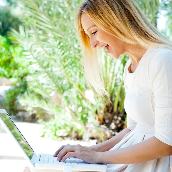 Όμορφη γυναίκα χρησιμοποιώντας φορητό υπολογιστή ενώ κάθεται χαλαρή στον πάγκο σε s — Φωτογραφία Αρχείου