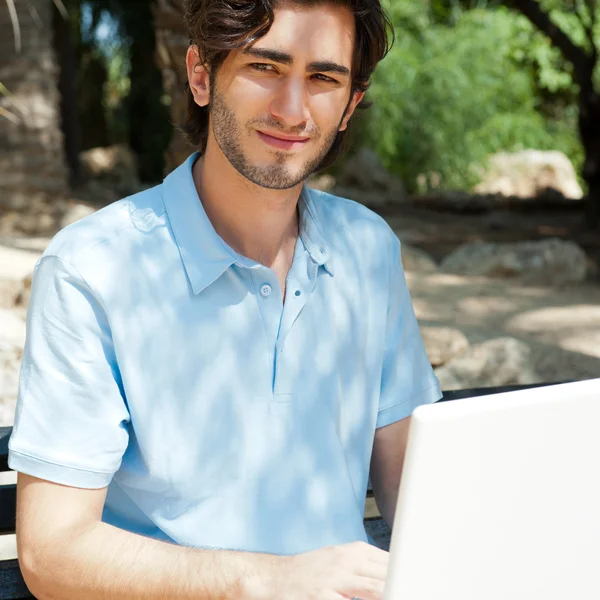 노트북 야외 벤치에 앉아와 젊은 남자의 초상화 — 스톡 사진