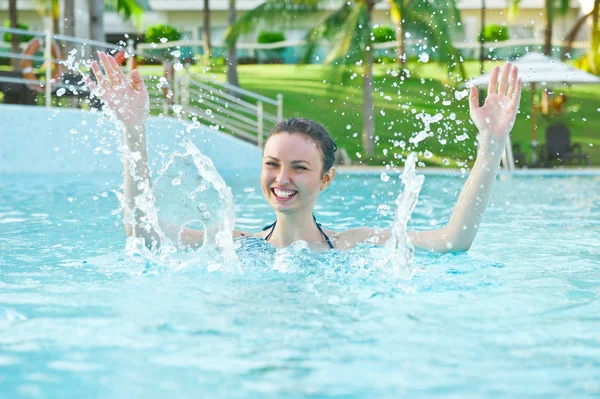 Kvinna i en pool som har kul med splash — Stockfoto