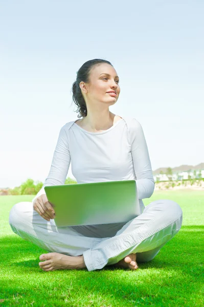 Ženské univerzitní student sedí na trávě, pracovat na notebooku v kampusu — Stock fotografie
