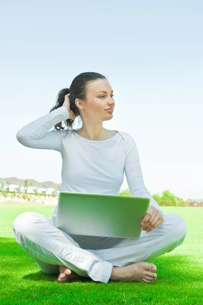 Studentin sitzt auf dem Rasen und arbeitet am Laptop auf dem Campus — Stockfoto