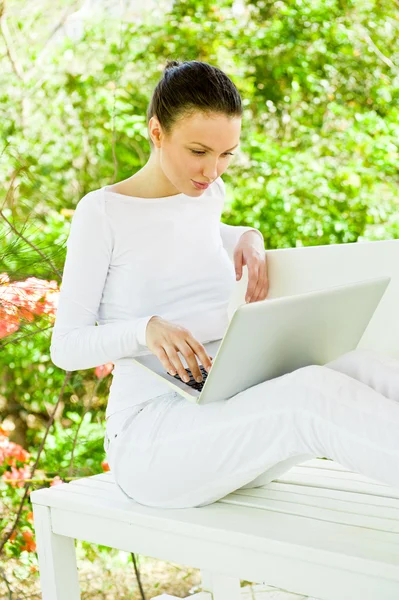 Gyönyörű nő használ laptop ülve ellazult, padon, Park nyári — Stock Fotó