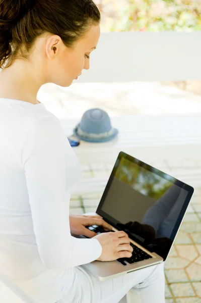 Businesswoman sitting on bench working on laptop in park wearing white clothes — Stock Photo, Image